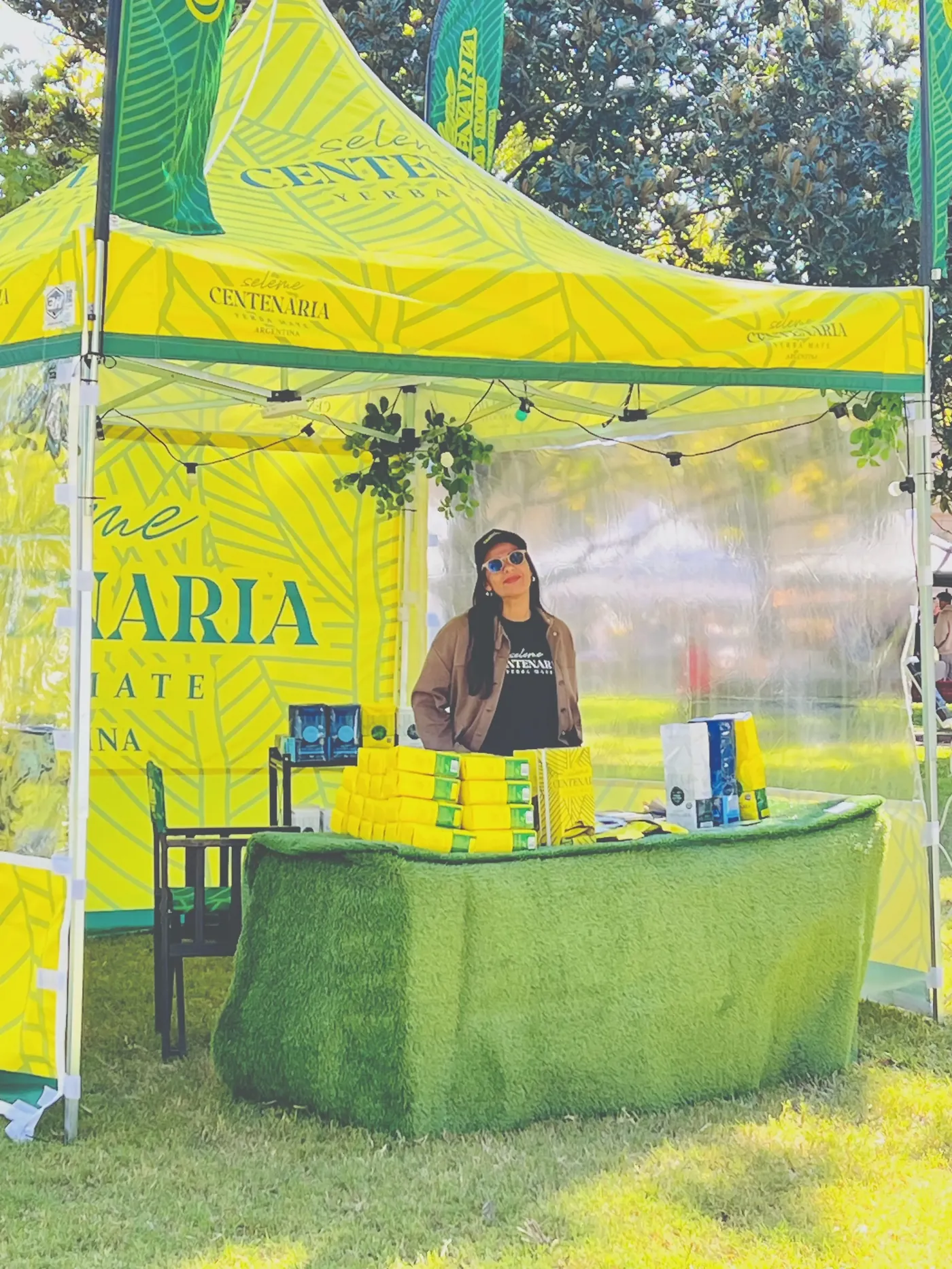 Carpa amarilla de Centenaria con mostrador en un evento al aire libre